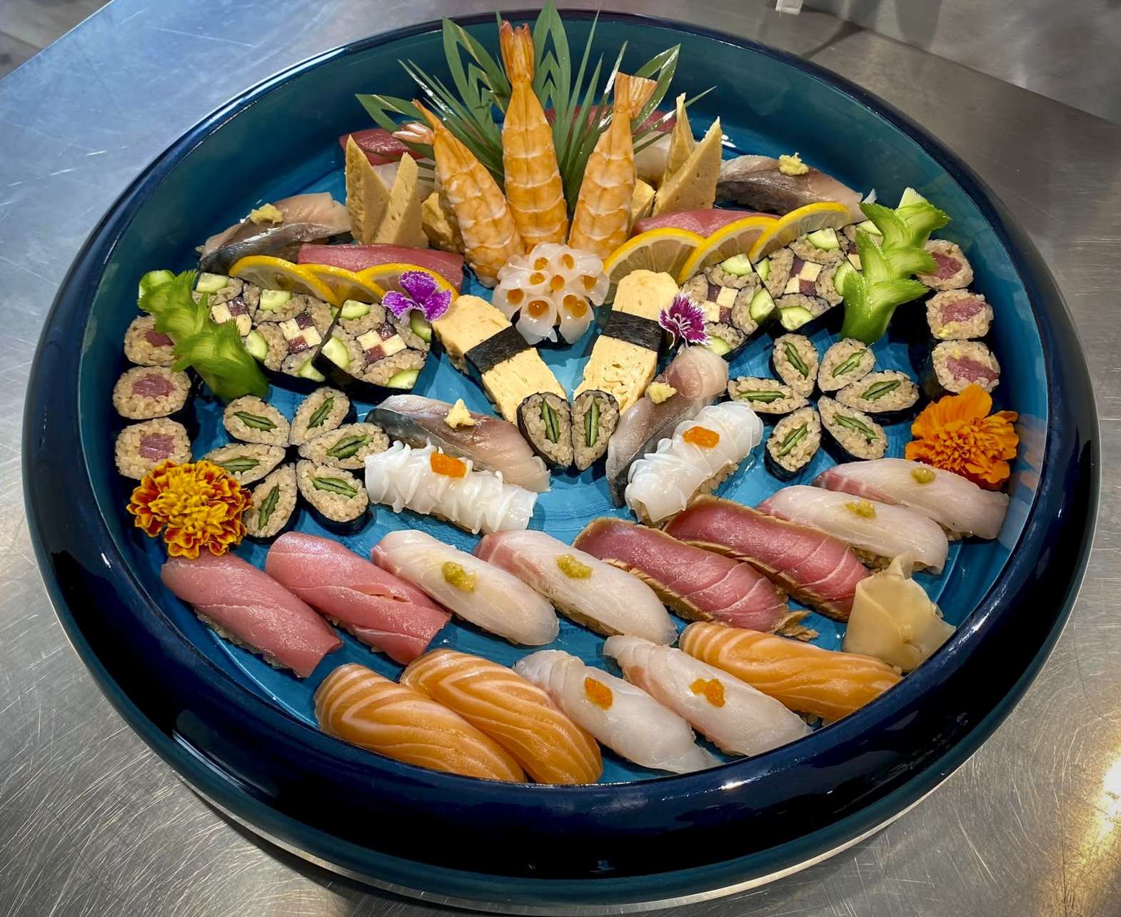 Round blue platter with a mosaic of bluefin tuna, salmon, tamago, hamachi and prawn nigiri
