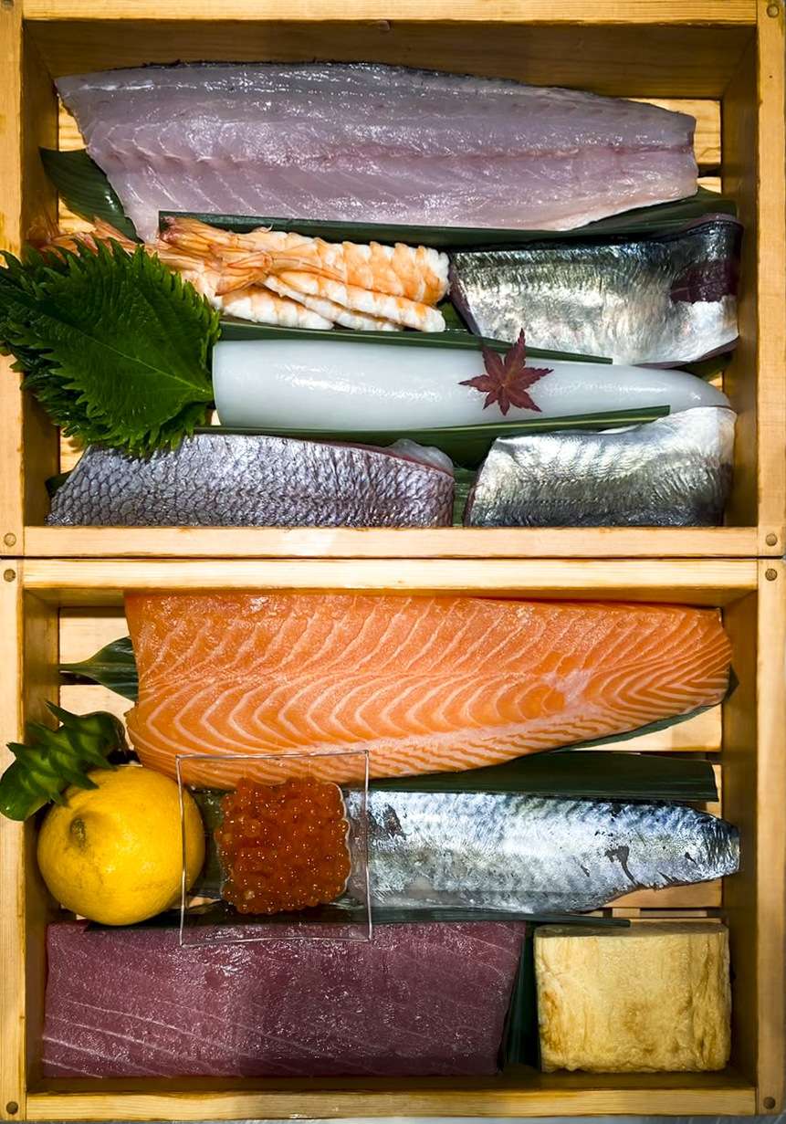 Wooden box with tuna, mackerel, horse mackerel, squid, prawns and sea bass ready to be cut