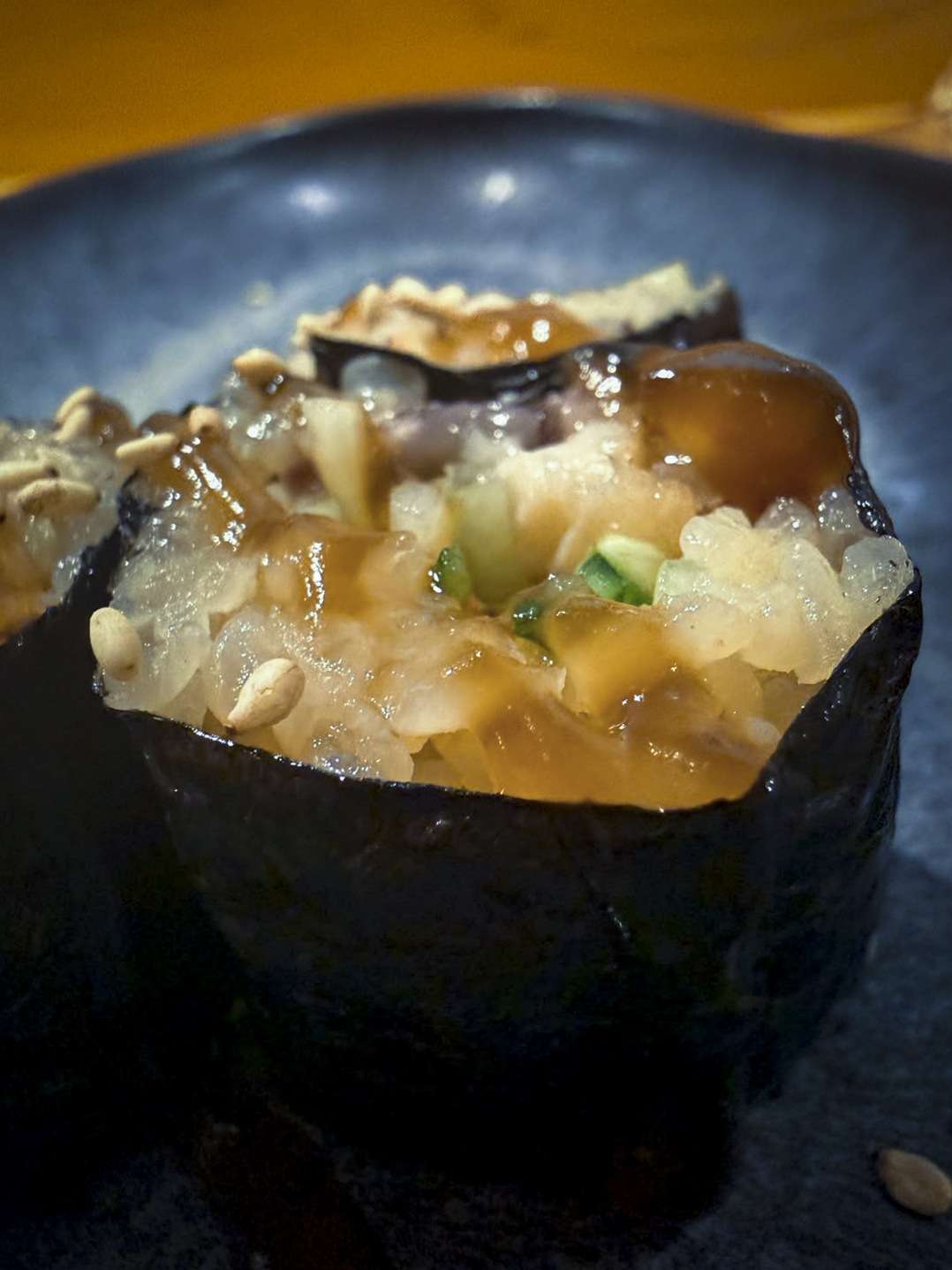 Eel maki wrapped in nori with sukiyaki sauce, on a stone plate